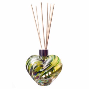 May include: Heart-shaped glass diffuser with a green and yellow swirl pattern. The diffuser has a silver-coloured neck and contains several wooden reeds. The design is decorative and suitable for home fragrance.