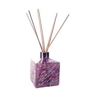 May include: A purple glass diffuser bottle with a silver lid and wooden sticks. The bottle has a swirl pattern.