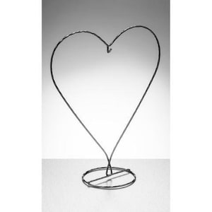 May include: A black metal heart-shaped stand with a round base. The stand is made of twisted wire and is ideal for displaying small items.