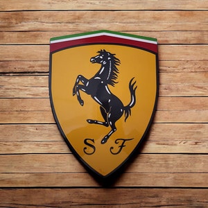 May include: A yellow shield-shaped logo with a black rearing horse and the letters "SF" in the center. The shield has a red and green stripe at the top.