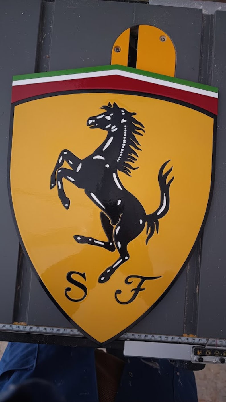 May include: A yellow shield-shaped sign with a black rearing horse and the letters "SF" in black. The shield has a red, white, and green stripe at the top.