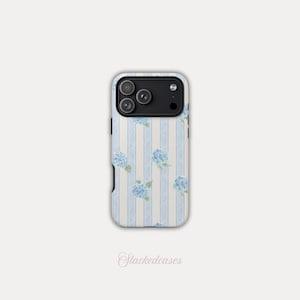May include: A phone case featuring a light blue and white striped pattern with blue hydrangea floral accents. The case has a black camera module and the text "Stackedcases" in a script font.
