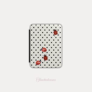 May include: A rectangular phone case with a white background and black polka dots. Four red ladybugs with black spots are scattered across the surface. The text "Stackedeases" is written in cursive at the bottom.
