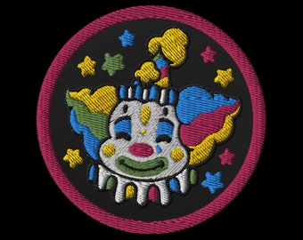 May include: A round embroidered patch with a sad clown face. The clown is wearing a yellow, blue, and pink hat and has a green smile. The background is black with white stars.