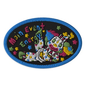May include: A black and blue oval embroidered patch with a colorful clown and the text "Main Event Energy!" in a rainbow font.