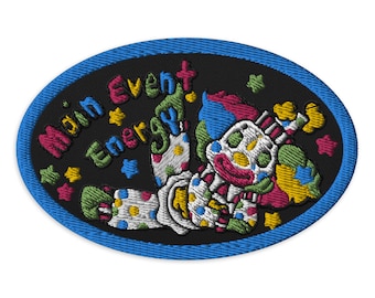 May include: A black and blue oval embroidered patch with a colorful clown and the text "Main Event Energy!" in a rainbow font.