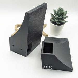 Puede incluir: Dos rampas de skate de pl&aacute;stico negro, una es un cuarto de tubo y la otra es un borde. El borde tiene la palabra "RMK" impresa.