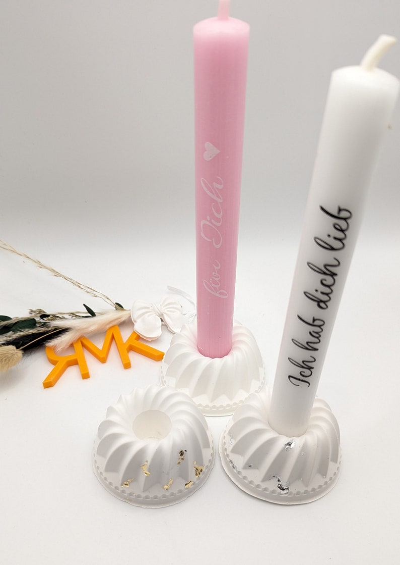 Peut inclure: Deux bougeoirs blancs avec une bougie rose et blanche. Les bougies portent l'inscription "Ich hab dich lieb" et "Ich lieb dich".