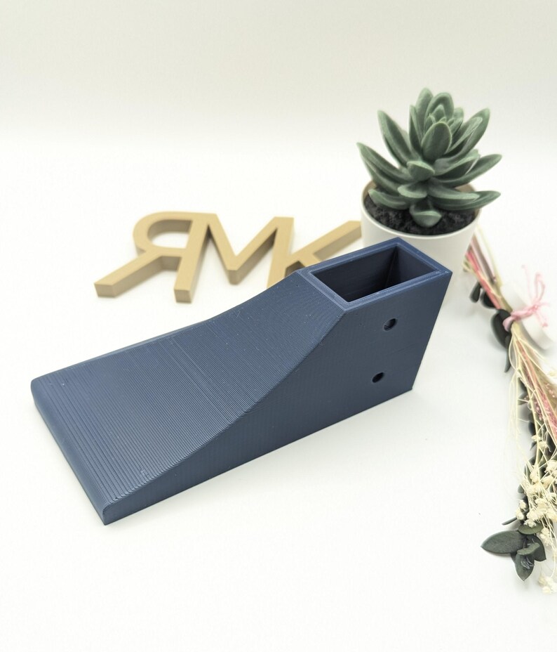 Puede incluir: Una rampa de color azul oscuro impresa en 3D con una peque&ntilde;a abertura rectangular en la parte superior. La rampa est&aacute; dise&ntilde;ada para usarse con coches de juguete u otros objetos peque&ntilde;os.