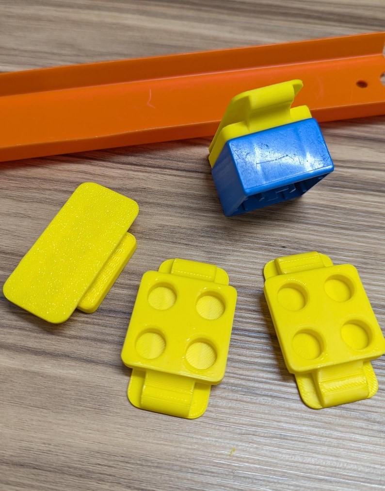 Peut inclure: Quatre pi&egrave;ces de piste en plastique jaune pour un circuit de voitures miniatures. Trois pi&egrave;ces ont quatre trous chacune et une pi&egrave;ce est un rectangle plat. Il y a aussi une pi&egrave;ce de connexion en plastique bleu.