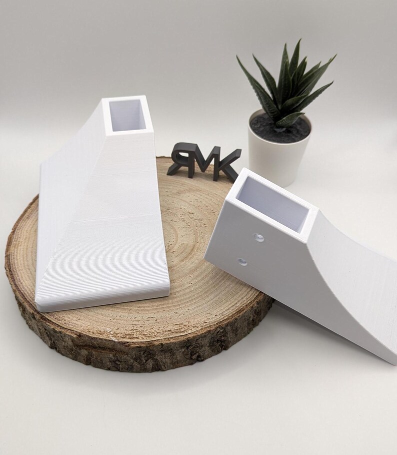 Puede incluir: Dos patas de muebles de pl&aacute;stico blanco con una parte superior cuadrada y una parte inferior curva. Las patas est&aacute;n sobre una superficie de madera.