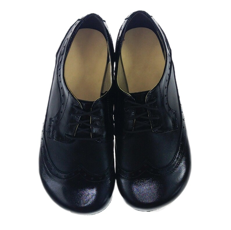 May include: A pair of black leather shoes with brogue detailing and lace-up closures.