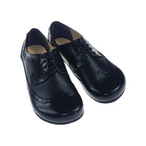 May include: A pair of black leather lace-up shoes with a brogue design. The shoes have a rounded toe and a low heel.