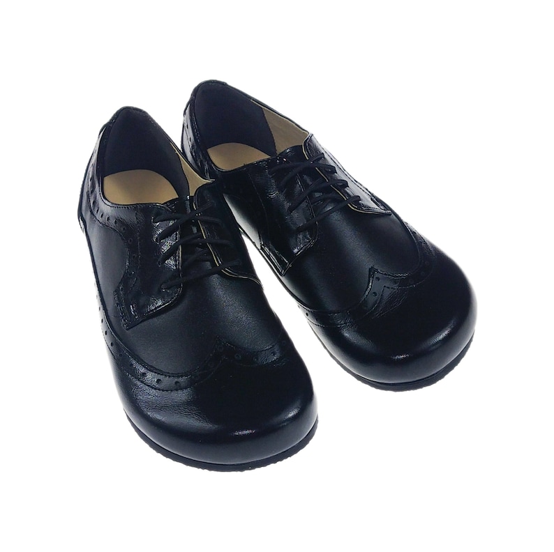May include: A pair of black leather lace-up shoes with a brogue design. The shoes have a rounded toe and a low heel.