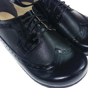 May include: A pair of black leather oxford shoes with a brogue design and lace-up closure.