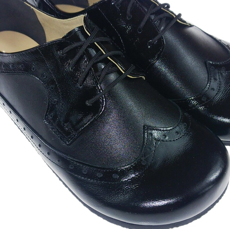 May include: A pair of black leather oxford shoes with a brogue design and lace-up closure.