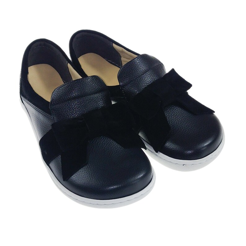 Pode incluir: Sapatos pretos de couro com um la&ccedil;o de veludo preto na frente.