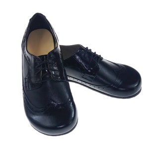 May include: A pair of black leather oxford shoes with brogue detailing. The shoes have laces and a rounded toe.