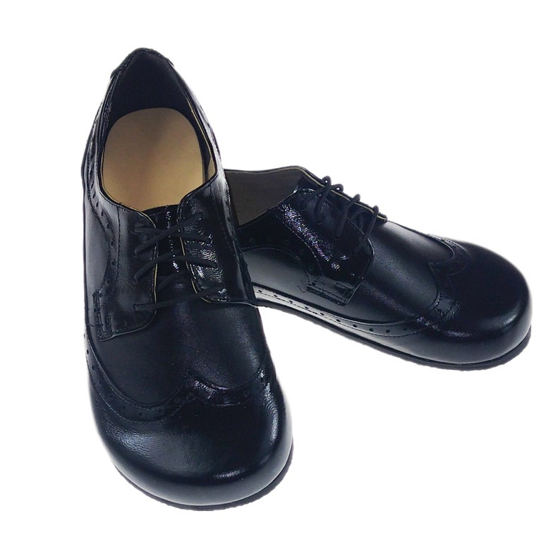 May include: A pair of black leather oxford shoes with brogue detailing. The shoes have laces and a rounded toe.