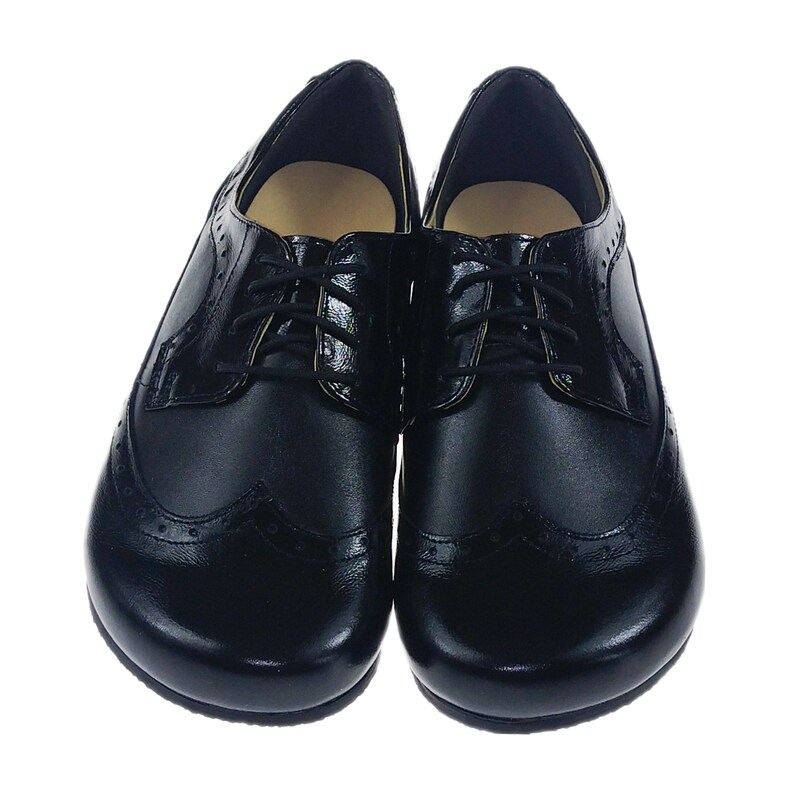 May include: A pair of black leather lace-up shoes with a wingtip design. The shoes have a rounded toe and a low heel.