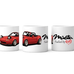 May include: White ceramic mug with a red sports car design. The car is shown from three angles. The mug also features the text "Miata Fueled by Love" in black and red. A great gift for car lovers.
