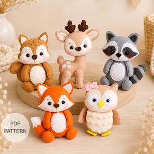 Puede incluir: Cinco peluches de fieltro que incluyen una ardilla marrón, un ciervo beige, un mapache gris, un zorro naranja y un búho beige con un lazo rosa. Un círculo blanco con el texto PDF PATTERN impreso en negro aparece en la parte inferior izquierda.