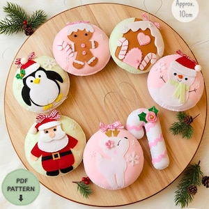 Peut inclure: Un ensemble de sept décorations de Noël en feutrine représentant un bonhomme en pain d'épices, une maison en pain d'épices, un pingouin, un bonhomme de neige, le Père Noël, un renne et un sucre d'orge. Chaque ornement mesure environ 10cm.