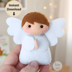 Könnte beinhalten: Handgefertigter Engel-Ornament aus Filz mit braunen Haaren, hellem Hautton und weißen Flügeln. Der Engel trägt ein weißes Gewand und hat eine Schnur zum Aufhängen. Das Ornament ist 9 cm groß und trägt die Aufschrift "Sofort-Download".
