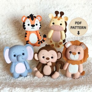 May include: Five felt animal figures including a tiger, giraffe, elephant, monkey, and lion. Each figure features stitched details and a soft appearance. A circular beige tag with the text PDF PATTERN and a downward arrow is visible in the corner.