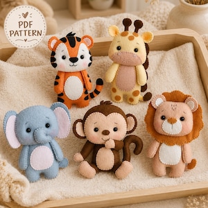 Può includere: Cinque peluche in feltro a forma di tigre, giraffa, elefante, scimmia e leone disposti su un vassoio di legno. La tigre è arancione con strisce nere, la giraffa gialla con macchie marroni, l'elefante blu, la scimmia marrone e il leone ha una criniera marrone. Un'etichetta circolare riporta la scritta PDF PATTERN.