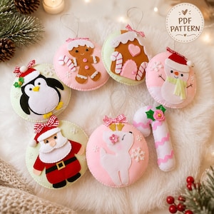 Pode incluir: Uma coleção de sete enfeites de Natal de feltro com um boneco de gengibre, uma casa de gengibre, um boneco de neve, um pinguim, o Pai Natal, uma rena e um bastão de doces. Cada enfeite tem um laço e o texto PDF PATTERN é visível.