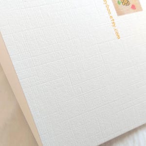 May include: White card with a textured surface. The back of the card has a small image of three yellow flowers and a red heart. The text "creationsbydaisyboo.etsy.com" is printed in gold on the back of the card.