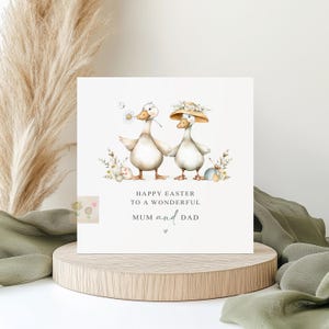 May include: Easter card with two geese, one with a daisy, the other wearing a floral hat. The card says "Happy Easter to a Wonderful Mum and Dad". Includes Easter eggs and floral decorations, perfect for Easter celebrations.