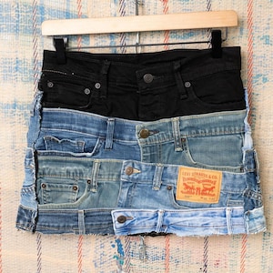 May include: A white ceramic mug with a black handle and the text "But First, Coffee" in a black, handwritten-style font. The mug is on a white surface.