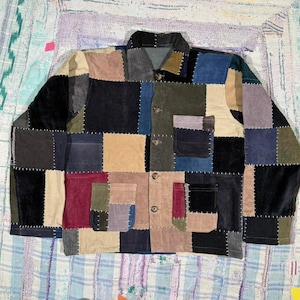 May include: A long-sleeve button-down jacket constructed from a patchwork of multi-coloured corduroy fabric squares. The garment features a collar, a single chest pocket, two lower front pockets, and visible white stitching outlining each fabric patch.