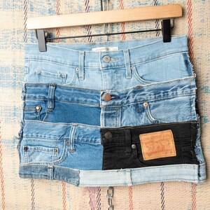 Peut inclure: Une jupe en jean patchwork composée de jeans recyclés, avec un assemblage de différents bleus et noirs. Elle présente des poches, des passants de ceinture et une étiquette Levi Strauss & Co.