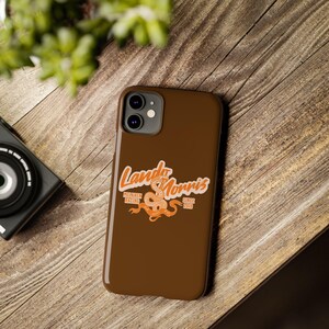 May include: A brown phone case with a graphic of a snake and the text "Lando Norris McLaren Racing Since 2019".