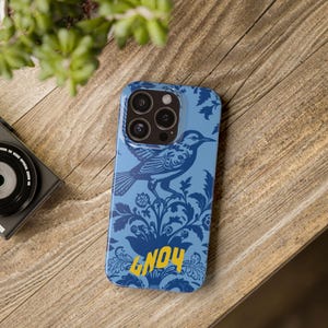 May include: A blue phone case with a floral pattern and a bird design. The case has a yellow inscription that says "GNO4".