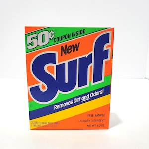 May include: A box of Surf laundry detergent, predominantly orange with the word "Surf" in large blue letters. The box includes green and yellow stripes, and text stating it removes dirt and odours. It contains a free sample and weighs 176 grams.