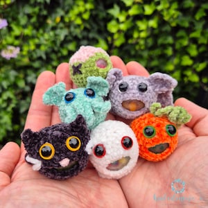 Könnte beinhalten: Eine Sammlung von sechs gehäkelten Halloween-Charakteren, darunter ein Geist, ein Kürbis, ein Zombie, eine Fledermaus, eine Katze und ein Tintenfisch. Jeder Charakter hat Glitz Augen und einen einzigartigen Ausdruck.