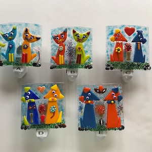 May include: Five colorful glass night lights featuring animal couples. Each night light has a blue and orange animal with a heart or flower between them. The night lights are labeled A through E.