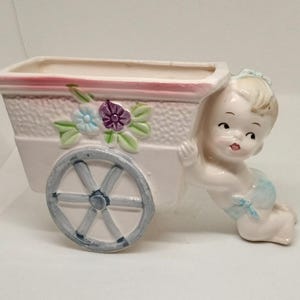 プランターとして使われる花カートを押す男の子。
