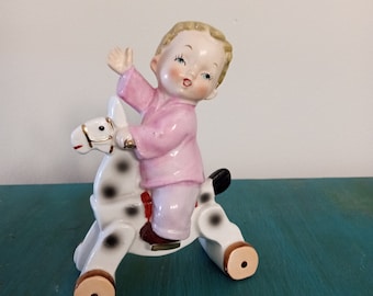 Waving boy on a rocking horse on wheels.