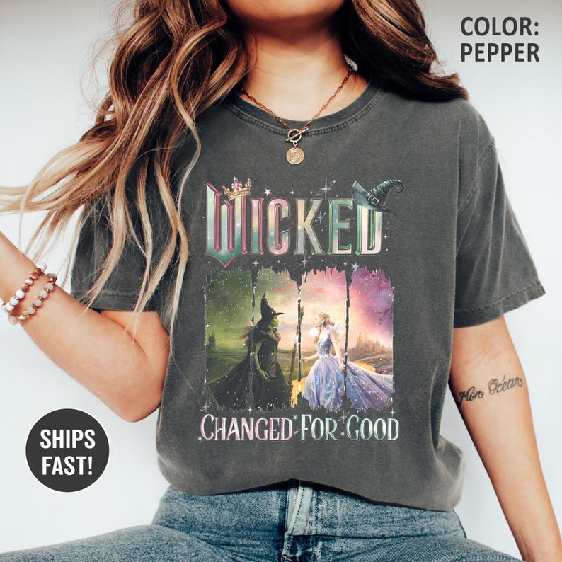 May include: Pepper-colored t-shirt featuring the word "Wicked" in a decorative font, with images of the Wicked Witch of the West and Glinda the Good Witch. The text "Changed for Good" is below the images. A witch hat and crown are also featured.