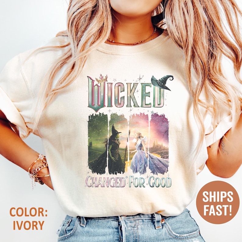 May include: Ivory-colored t-shirt featuring the word "WICKED" above a graphic of two witches and a princess. The text "CHANGED FOR GOOD" is below the graphic. A witch hat graphic is above the word "WICKED".