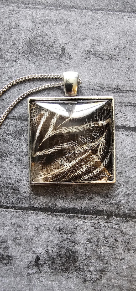 Feathers resin sealed in a glass pendant necklace