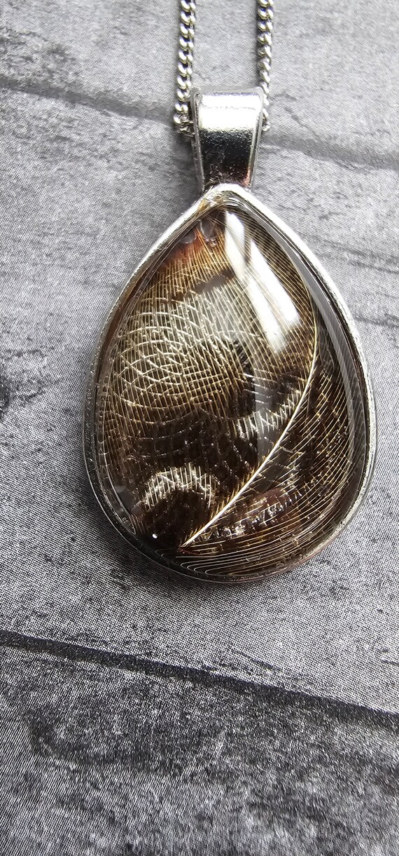Necklace with natural bird feather resin sealed in a glass cabochon pendant