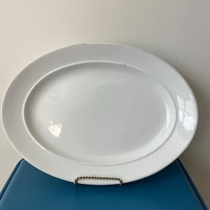 May include: A large, white oval serving platter with a raised rim. The platter is made of ceramic and has a glossy finish.