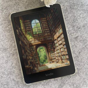 May include: A Kindle e-reader with a clear protective case displays a detailed image of a library interior with bookshelves and a window. The word "kindle" is printed at the bottom. A white flower rests on a gray surface.