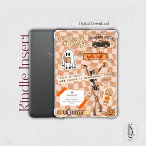 May include: Kindle insert with a seasonal autumn design. The cover has a brown and orange checkered pattern, with illustrations of a ghost, skeleton, pumpkins, and the text "in my spooky era" and "hello fall".